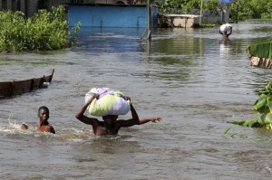 People wade through a flood with their belongings after their houses were submerged in the Amassoma community in Bayelsa state