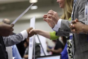 Corporate recruiters gesture and shake hands as they talk with job seekers at a Hire Our Heroes job fair targeting unemployed military veterans and sponsored by the Cable Show, a cable television industry trade show in Washington