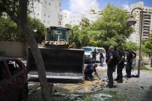 Israeli police survey the scene after a rocket fired from Gaza landed in Ashdod