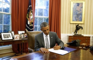 U.S. President Barack Obama signs H.J. Res. 76, Emergency Supplemental Appropriations Resolution, 2014, while in the Oval Office in the White House in Washington