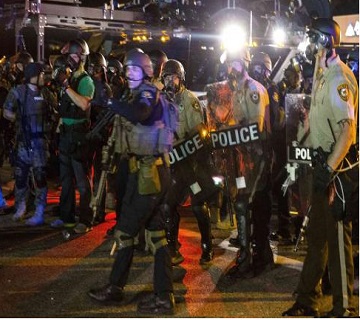 A line of police officers yells at a crowd of rowdy demonstrators during further protests in reaction to the shooting of Michael Brown near Ferguson, Missouri