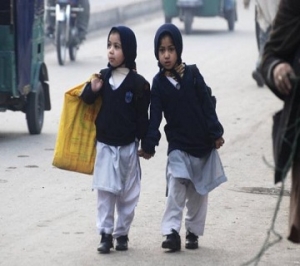 Girls carry their school bags as they walk along a road while heading to their school after it reopened in Peshawar