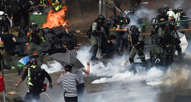 Riot police (R) make arrests as protesters (L) attempt to find safe passage out of the Hong Kong Polytechnic University campus in Hung Hom district of Hong Kong on November 18, 2019.