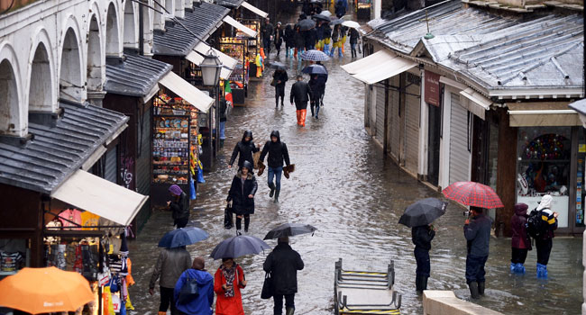 People walk in the flooded street near Rialto bridge, on November 15, 2019 in Venice, two days after the city suffered its highest tide in 50 years. Filippo MONTEFORTE / AFP