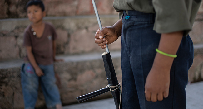 A boy aims a makeshift rifle as children are tought to use weapons by the Regional Coordinator of Community Authorities (CRAC-PF) community police force at a basketball court in the village of Ayahualtempan, Guerrero State, Mexico, on January 24, 2020. Pedro PARDO / AFP
