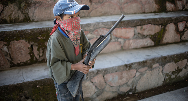 A boy holds a makeshift rifle as the Regional Coordinator of Community Authorities (CRAC-PF) community police force teaches a group of children how to use weapons, at a basketball court in the village of Ayahualtempan, Guerrero State, Mexico, on January 24, 2020. Pedro PARDO / AFP