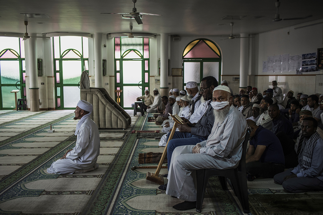 A Muslim man wearing a makeshift mask as a preventive measure against the COVID-19 coronavirus sits with other worshippers the beginning of the Friday prayer at the 23rd Street Mosque in the predominantly Muslim neighbourhood of Mayfair, Johannesburg, on March 20, 2020. - The mosque implemented a double shift prayer schedule to respect the instructions given by the South African Government limiting to 100 hundred the number of people per religious gathering. Photo: AFP