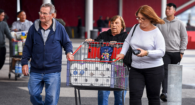 People leave a Costco warehouse with rolls of toilet paper amongst their groceries in Melbourne on March 5, 2020. William WEST / AFP