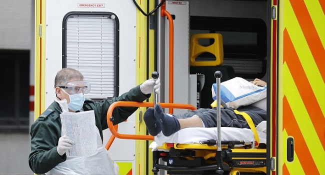 File: A member of the ambulance services assists in moving a patient from an ambulance to St Thomas' Hospital in London on March 31, 2020, as the country is under lockdown due to the novel coronavirus COVID-19 pandemic. Tolga AKMEN / AFP.