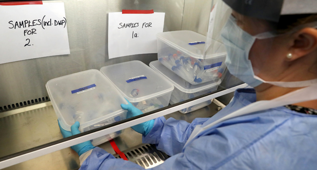 A laboratory technician wearing full PPE (personal protective equipment) holds a container of test tubes containing live samples taken from people tested for the novel coronavirus, at a new Lighthouse Lab facility dedicated to the testing for COVID-19, at Queen Elizabeth University Hospital in Glasgow on April 22, 2020. Andrew Milligan / POOL / AFP