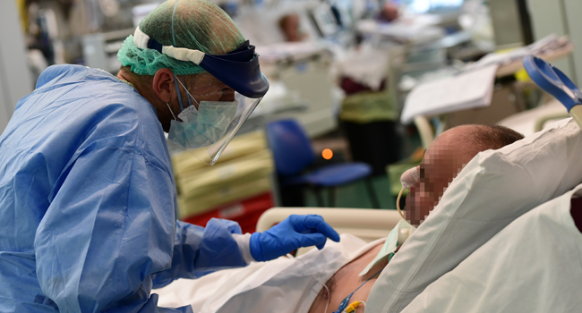 A member of the medical staff wearing personal protective equipment (PPE) speaks with a patient in the COVID-19 unit of the Policlinico Sant'Orsola-Malpighi hospital in Bologna on April 15, 2020, during a lockdown aimed at curbing the spread of the COVID-19 pandemic, caused by the novel coronavirus. Miguel MEDINA / AFP
