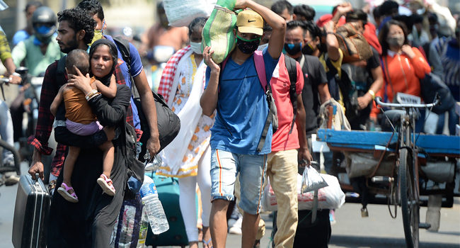 Stranded migrant labourers walk to an assembling centre to get transferred to a railway station to board on a special train to Bihar after the government eased a nationwide lockdown imposed as a preventive measure against the COVID-19 coronavirus, in Chennai on May 30, 2020. Arun SANKAR / AFP