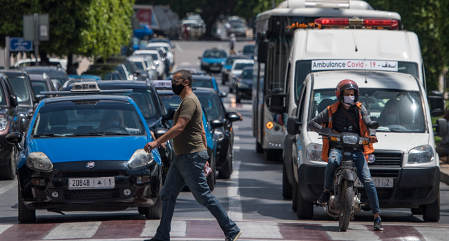 A man, wearing a protective mask due to the COVID-19 pandemic, crosses a street while drivers wait at a traffic light in the Moroccan capital Rabat on June 10, 2020, as the government declared the extension of coronavirus lockdown until July 10. FADEL SENNA / AFP