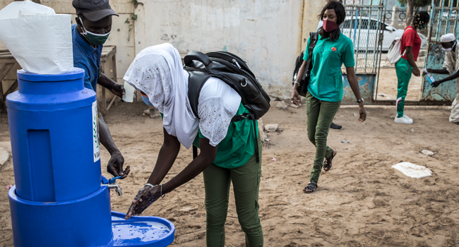 A High School student at the Lycee Blaise Diagne washes her hands as she arrives for her first day back at school in Dakar on June 25, 2020. JOHN WESSELS / AFP