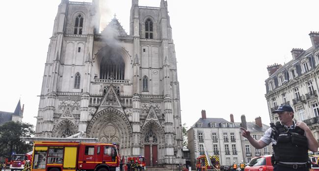 A French Police officer gestures as firefighters are at work to put out a fire at the Saint-Pierre-et-Saint-Paul cathedral in Nantes, western France, on July 18, 2020. Sebastien SALOM-GOMIS / AFP