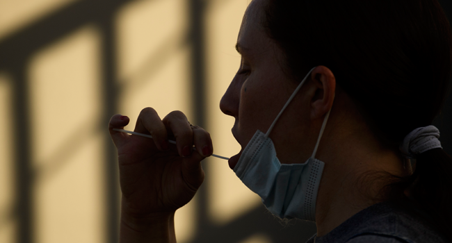 A person takes a Covid-19 oral swab test at a pop-up community testing site in the Panorama City neighborhood of Los Angeles, California, December 9, 2020. Patrick T. Fallon / AFP