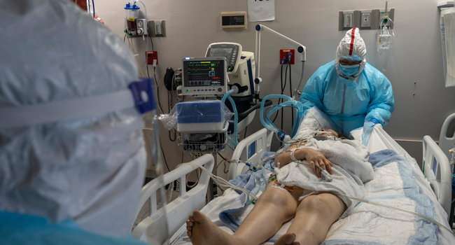 Medical staff members Flor Trevino (L) and Susan Paradela attempt to change the bed sheet of a patient in the COVID-19 intensive care unit (ICU) at the United Memorial Medical Center on December 7, 2020 in Houston, Texas. Go Nakamura/Getty Images/AFP