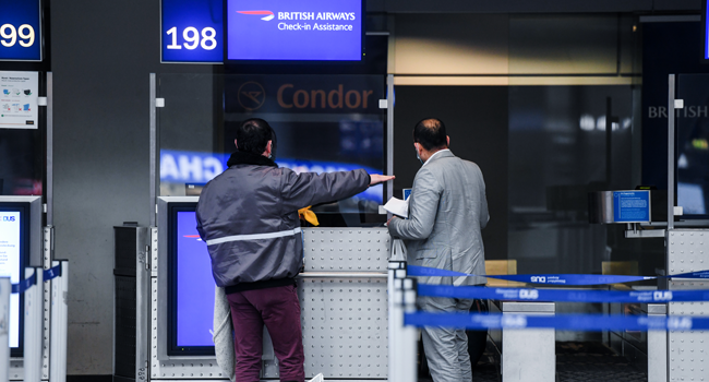 Passengers stand at the check-in of British Airways for a flight to London at Duesseldorf Airport in Duesseldorf, western Germany, on December 21, 2020, amid the ongoing novel coronavirus / COVID-19 pandemic. Ina FASSBENDER / AFP