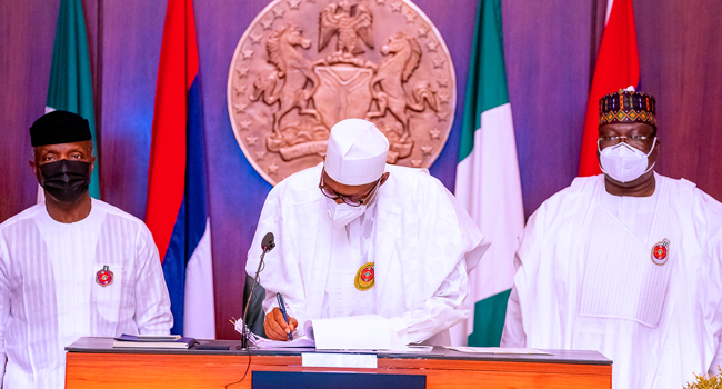 President Muhammadu Buhari, flanked by Vice President Yemi Osinbajo (L) and Senate President Ahmed Lawan (R), signed the 2021 budget into law on December 31, 2020. Credit: Bayo Omoboriowo/State House
