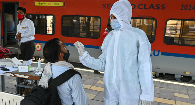 A health worker takes a nasal swab sample of a passenger for the Covid-19 coronavirus test after arriving at a railway platform on a long distance train, in Mumbai on April 14, 2021. Punit PARANJPE / AFP