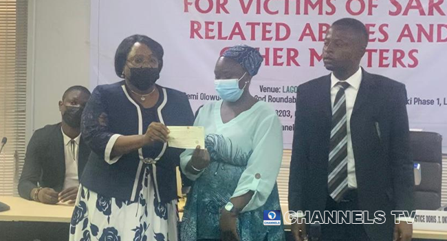 Chairman of the Lagos State Judicial Panel, Justice Doris Okuwobi, hands over a cheque to Bolanle Amudalat Kareem and her lawyer, Aderemi Aka on May 15, 2021.