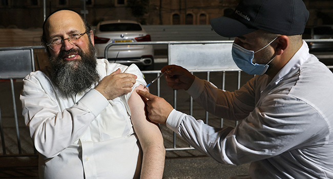 An Israeli health worker administers a third dose of the Pfizer-BioNtech Covid-19 vaccine to Jewish ultra-Orthodox man at a religious neighbourhood in Jerusalem on August 19, 2021. AHMAD GHARABLI / AFP