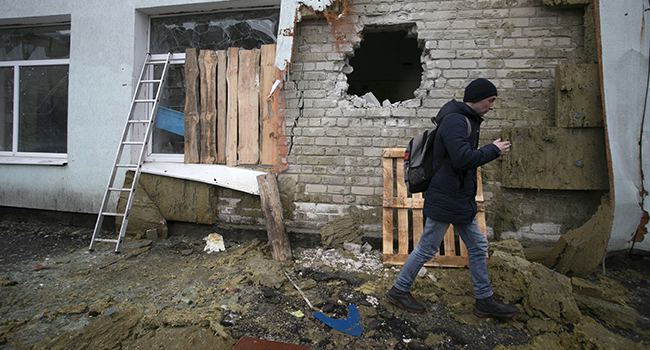 A local resident of the Ukrainian-controlled village of Stanytsia Luhanska, Luhansk region, walks among debris after the shelling by Russia-Backed separatists on February 18, 2022. Aleksey Filippov / AFP