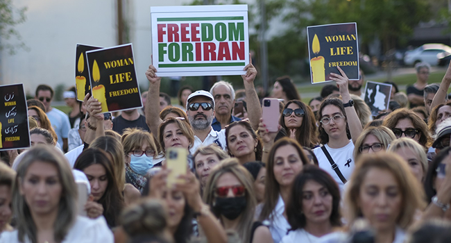 People take part in a candlelight vigil for Mahsa Amini who died in custody of Iran's morality police, in Los Angeles, California, September 29, 2022. (Photo by RINGO CHIU / AFP)