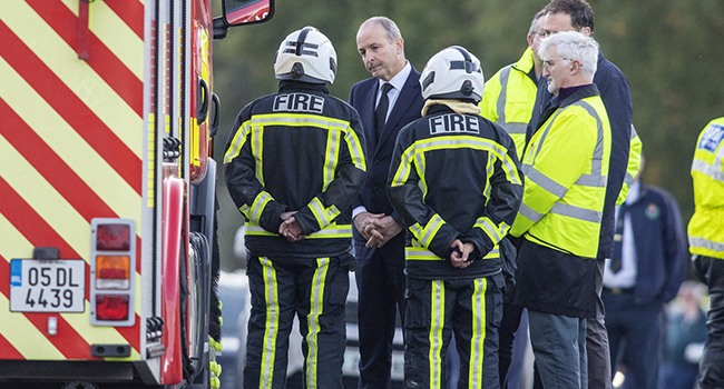 Ireland's Prime Minister Micheal Martin speaks to emergency service workers near the scene of an explosion at a petrol station in Creeslough, in the north-west of Ireland on October 8, 2022. (Photo by Paul Faith / AFP)