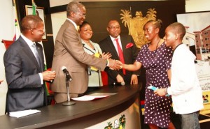 Governor, Babatunde Fashola presenting a key to the winner of the Shitta Scheme, Lagos HOMS, Mrs. Yetunde Oluwaseun and her son, Master Joseph Camille.