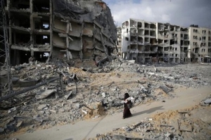 A Palestinian woman walks past destroyed buildings in Beit Lahiya in the northern Gaza Strip
