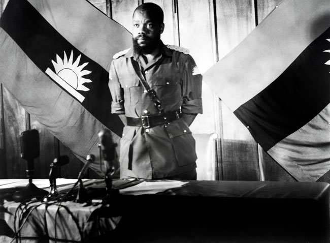 In this file photograph taken on August 16, 1967, Colonel Odumegwu Emeka Ojukwu, the leader of the breakaway Republic of Biafra, stands in front of a Biafra flag as he addresses a press conference in Enugu. AFP