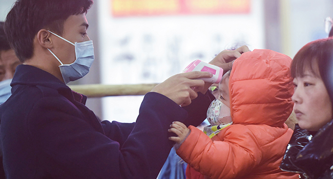A staff member (L) checks body temperature of a child after a train from Wuhan arrived at Hangzhou Railway Station in Hangzhou, China's eastern Zhejiang province. STR / AFP