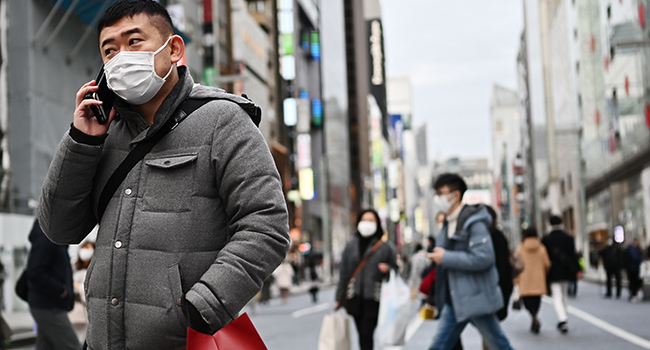 Pedestrians wearing protective masks to help stop the spread of a deadly virus which began in the Chinese city of Wuhan, walk on a street in Tokyo's Ginza area on January 25, 2020. CHARLY TRIBALLEAU / AFP