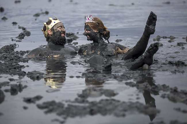 A couple of revellers enjoy the mud during the "Bloco da Lama", a mud carnival party, in Paraty, Rio de Janeiro state, Brazil, on February 22, 2020. - "Bloco da Lama" started in 1986 with teenagers playing with mud and became a traditional event at the historical city of Paraty. Photo by DANIEL RAMALHO / AFP