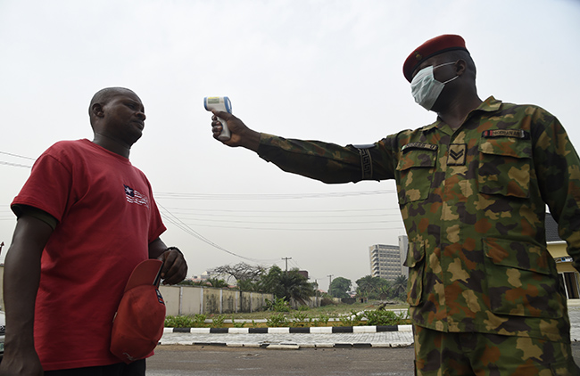 A soldier checks the body temperature of a visitor to the 68 Nigerian Army Reference Hospital at Yaba in Lagos, on February 28, 2020. - Nigeria reported the first new coronavirus case in sub-Saharan Africa on February 28, 2020 and a major global auto show was cancelled in a bid to stop contagion, as the deadly epidemic sent global stock markets and oil prices plunging. Photo: PIUS UTOMI EKPEI / AFP