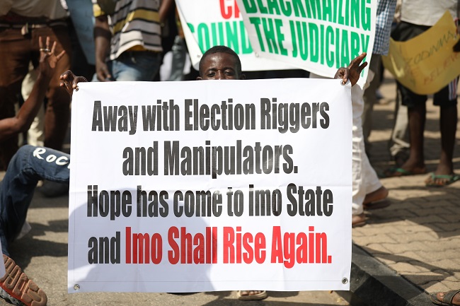 APC Supporters display placards during a protest in Abuja, while aslo asking Supreme Court To Maintain Judgement On Imo Election. PHOTO: Sodiq Adelakun