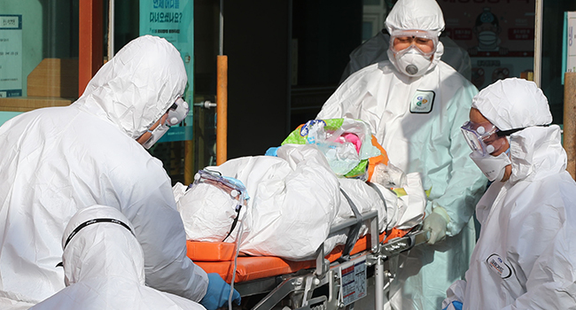Medical workers wearing protective gear transfer a suspected coronavirus patient (C) to another hospital from Daenam Hospital where a total of 16 infections have now been identified with the COVID-19 coronavirus, in Cheongdo county near the southeastern city of Daegu on February 21, 2020. YONHAP / AFP
