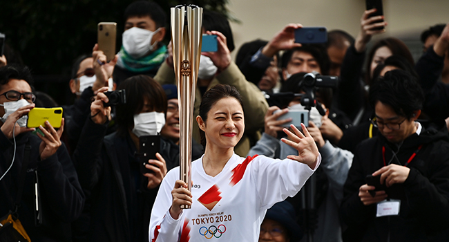 Japanese actress Satomi Ishihara waves while holding an Olympic torch during a rehearsal of the Tokyo 2020 Olympics torch relay in Tokyo on February 15, 2020. CHARLY TRIBALLEAU / AFP