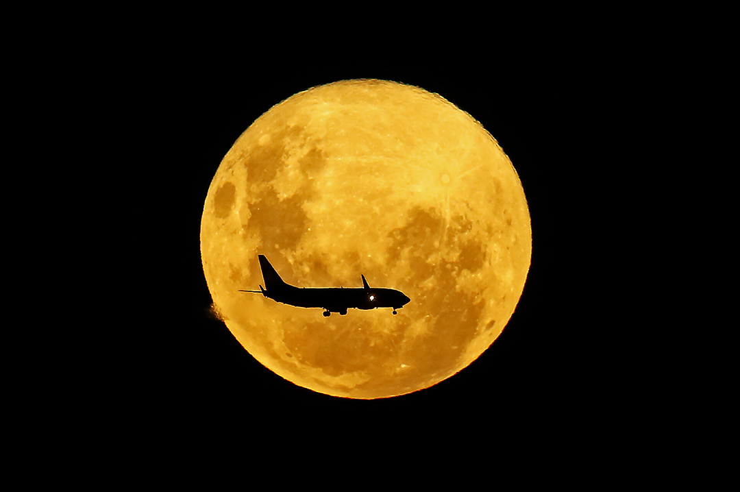 A plane passes in front of the full moon as seen from Curitiba, Brazil on March 9, 2020. - The supermoon is visible as the full moon coincides with the satellite in its closest approach to Earth, which makes it appear brighter and larger than other full moons. Photo: Heuler Andrey / AFP