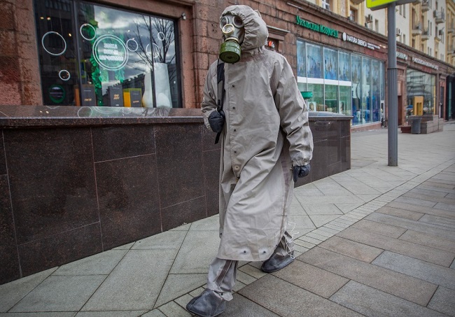 A man wears a protective suit and a gas mask as he walks along a street in central Moscow on March 21, 2020