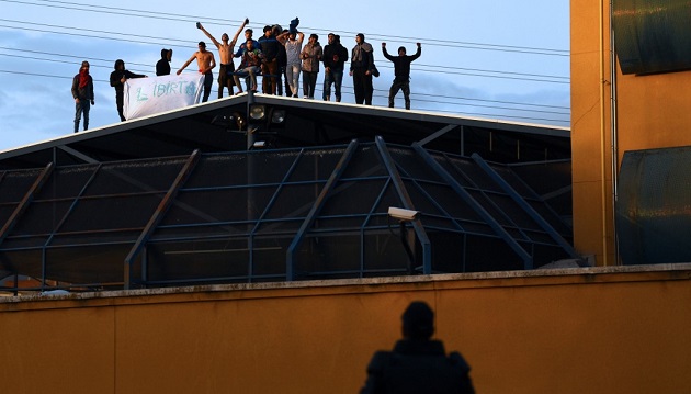 A police officer watches a group of illegal immigrants protesting on the roof of the Aluche Immigration Detention Center