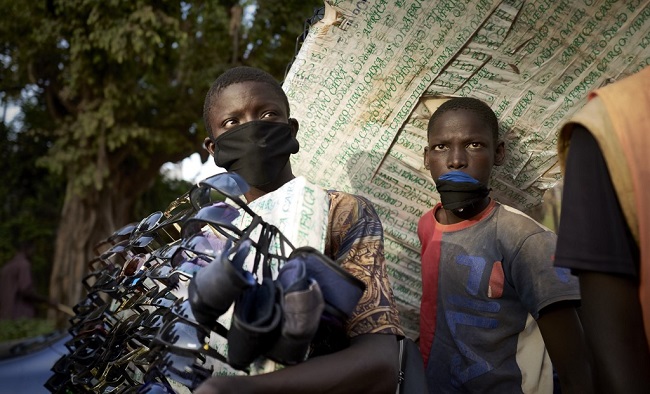 A street vendor sells sunglasses and masks in front of a supermarket of Bamako on March 26, 2020.