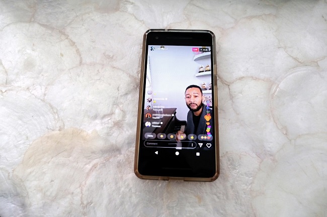 This image has been altered: Instagram handles of commenters have been blurred.) In this photo illustration, John Legend is seen on a smart phone performing on Instagram Live during the coronavirus outbreak on March 16, 2020 in Los Angeles, California.