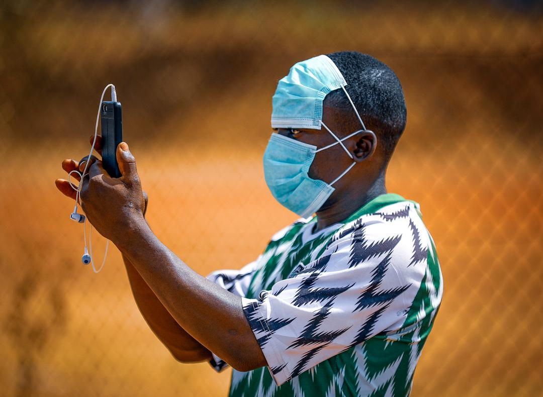 A boy wearing two face-masks records with his phone during a football match for international women’s day in Abuja on March 5, 2020. Photo: Sodiq Adelakun/ Channels TV