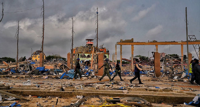 Security officials patrol through the rubble left behind after the explosion. Photo Credit: LASG