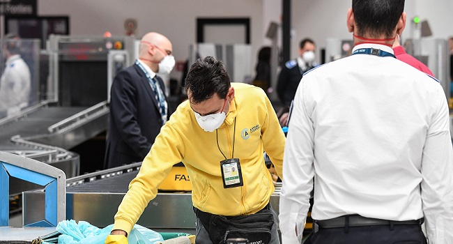 An airport cleaning staff, wearing a respiratory mask (C), controls baskets at Rome's Fiumicino international airport March 13, 2020. - Rome's Ciampino airport will shut to passenger flights from March 13, authorities said, with a Terminal T1 also closing at the city's main Fiumicino facility next week as airlines slash flights to Italy over the coronavirus outbreak. Andreas SOLARO / AFP.