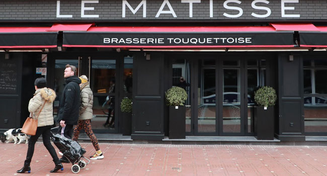 Pedestrians walk past a closed resteraunt in Le Touquet, northern France on March 15, 2020, as France battles the coronavirus that causes the COVID-19 disease. 