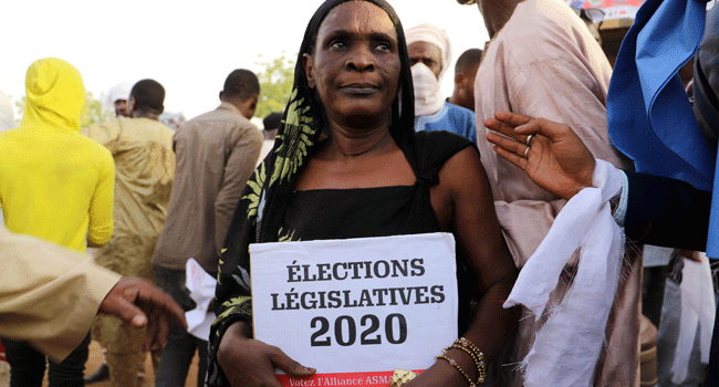 A woman holds an electoral poster as she gathers with supporters of the Alliance for Solidarity in Mali (ASMA) in Gao during a campaign event on March 18, 2020. Souleymane Ag Anara / AFP