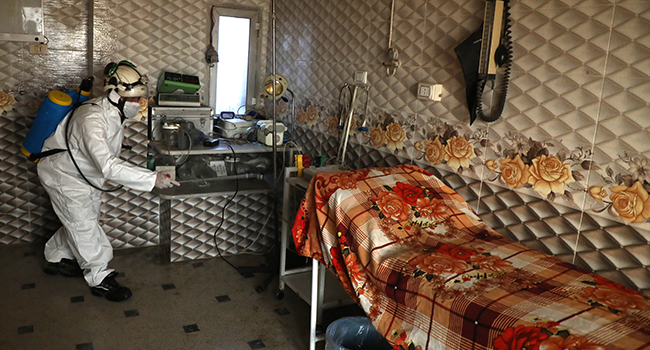 A member of the Syrian Civil Defence known as the "White Helmets" disinfects a hospital room, as part of preventive measures taken against infections by the novel coronavirus, in the Syrian town of Dana, east of the Turkish-Syrian border in the northwestern Idlib province, on March 22, 2020. AAREF WATAD / AFP